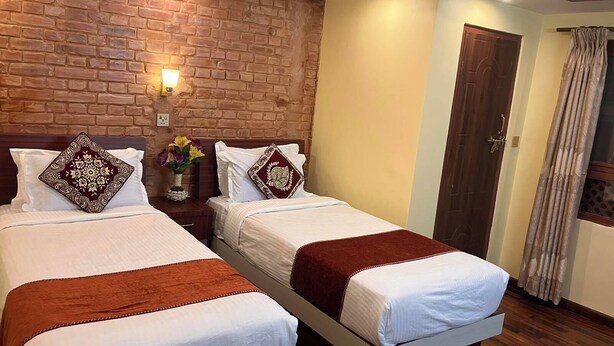 Ein Hotelzimmer mit zwei Betten, einer Ziegelwand, einer Holztür und einem Vorhang.