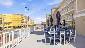 Ein Balkon mit Sitzgelegenheit, ein Pool und ein Gebäude mit gelber Fassade.