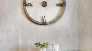 Un comedor con un reloj de pared redondo, una mesa con sillas y una planta en maceta.