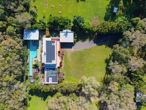 Vue aérienne d’une propriété dotée d’une piscine, de panneaux solaires et d’un grand jardin.