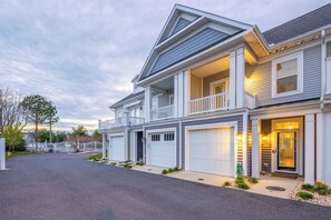 A two-story residential house with a front porch, a garage, and a driveway. - Luxury Shoal Harbor Retreat – Walk to Beach + Pool (Rehoboth Beach)