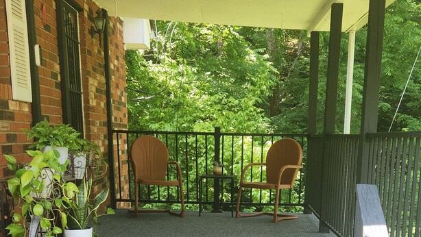 Un espacio al aire libre techado con una escalera que conduce a una zona de estar con dos sillas y una mesita.