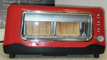 A red toaster with a transparent bread slot, a defrost button, a reheat button, and a bagel button.