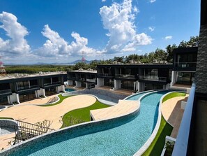 A modern hotel with a large swimming pool, multiple buildings, and a clear view of the surrounding landscape. - Tierra Utopia (Mai Khao)