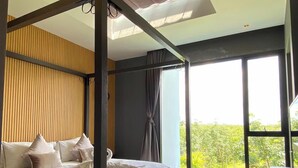 Une chambre moderne avec un lit à baldaquin, de grandes fenêtres et une vue sur la verdure.