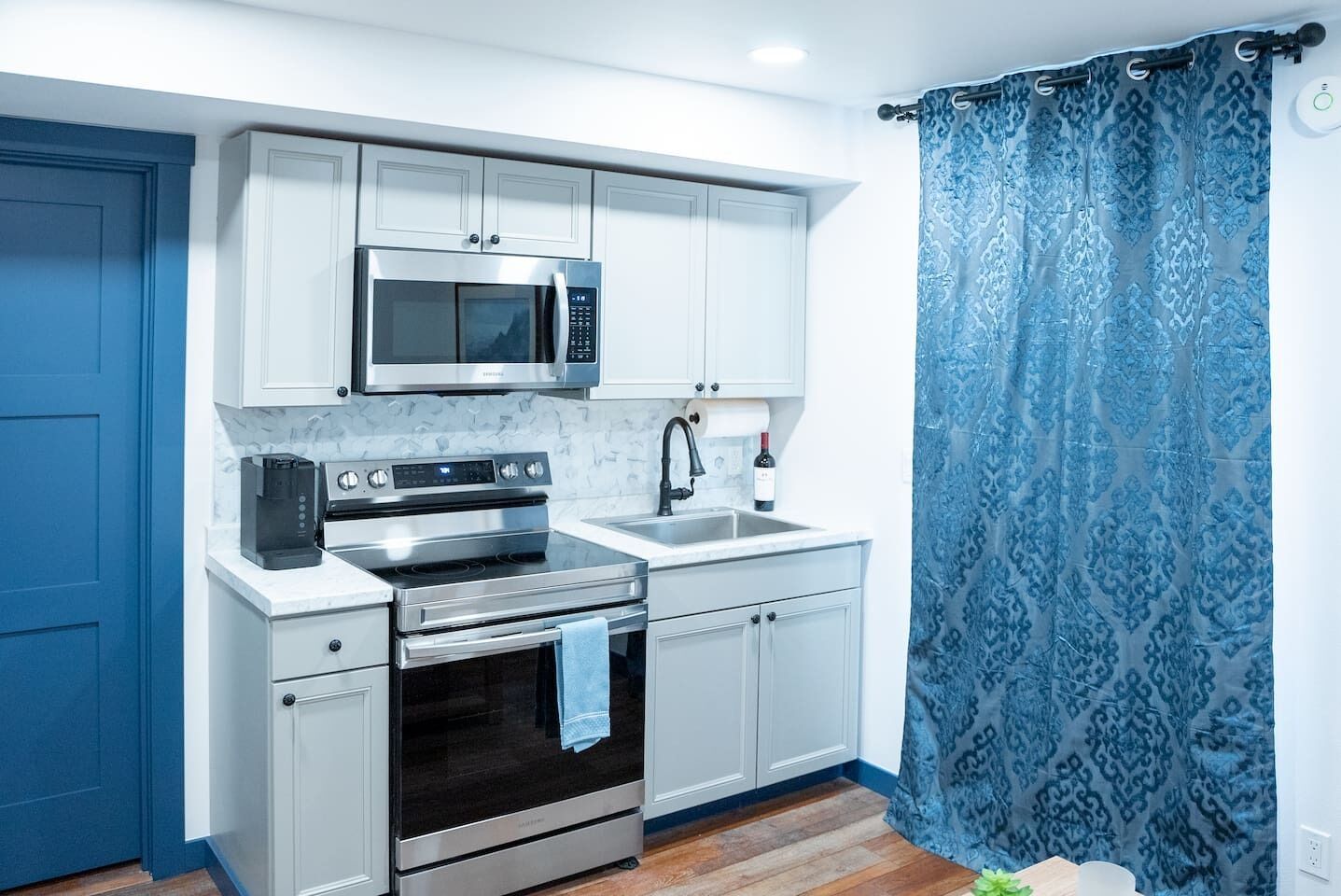 A compact kitchen with a microwave, stove, and sink.
