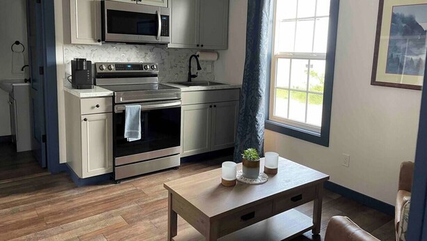 Una cocina moderna con electrodomésticos de acero inoxidable, una mesa de madera y un ventanal con vistas.
