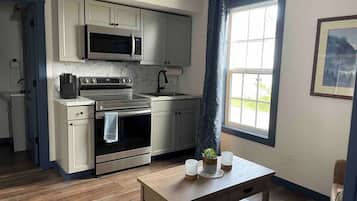 A modern kitchen with stainless steel appliances, a wooden table, and a window with a view.
