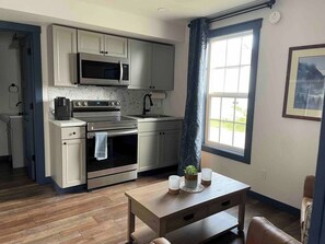 A modern kitchen with stainless steel appliances, a wooden table, and a window with a view. - Vasanoja Suite 102, Hyland Hotel (Palmer)