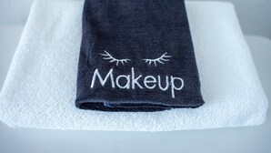 A black towel with the word "Makeup" and an embroidered eye design on a white towel. - Van Wormer Room 201, Hyland Hotel (Palmer)