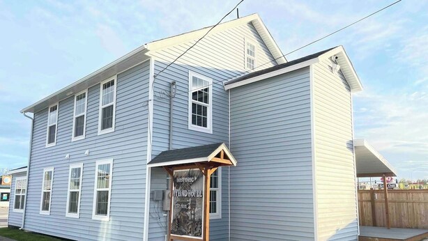 A two-story building with a porch and a signboard. - Bugge Room 203, Hyland Hotel (Palmer)