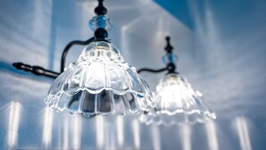 Two clear glass chandeliers with a simple, elegant design, hanging from a ceiling with a visible light fixture. - Werner Room 204, Hyland Hotel (Palmer)