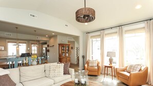 Ein geräumiges Wohnzimmer mit einer Couch, zwei Sesseln, einem Couchtisch und einem Essbereich mit Tisch und Stühlen.