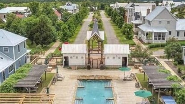 Ein Wohngebiet mit einem zentralen Pool, umgeben von Häusern und Grünflächen.