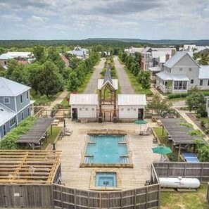 Zona residencial con piscina central, rodeada de casas y vegetación.