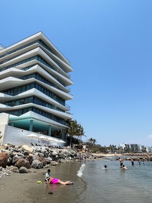 A modern hotel with a multi-story structure, a pool area, and a beachside location.