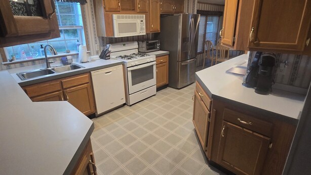 Una cocina con armarios de madera, un microondas, una estufa, un refrigerador y un lavabo.