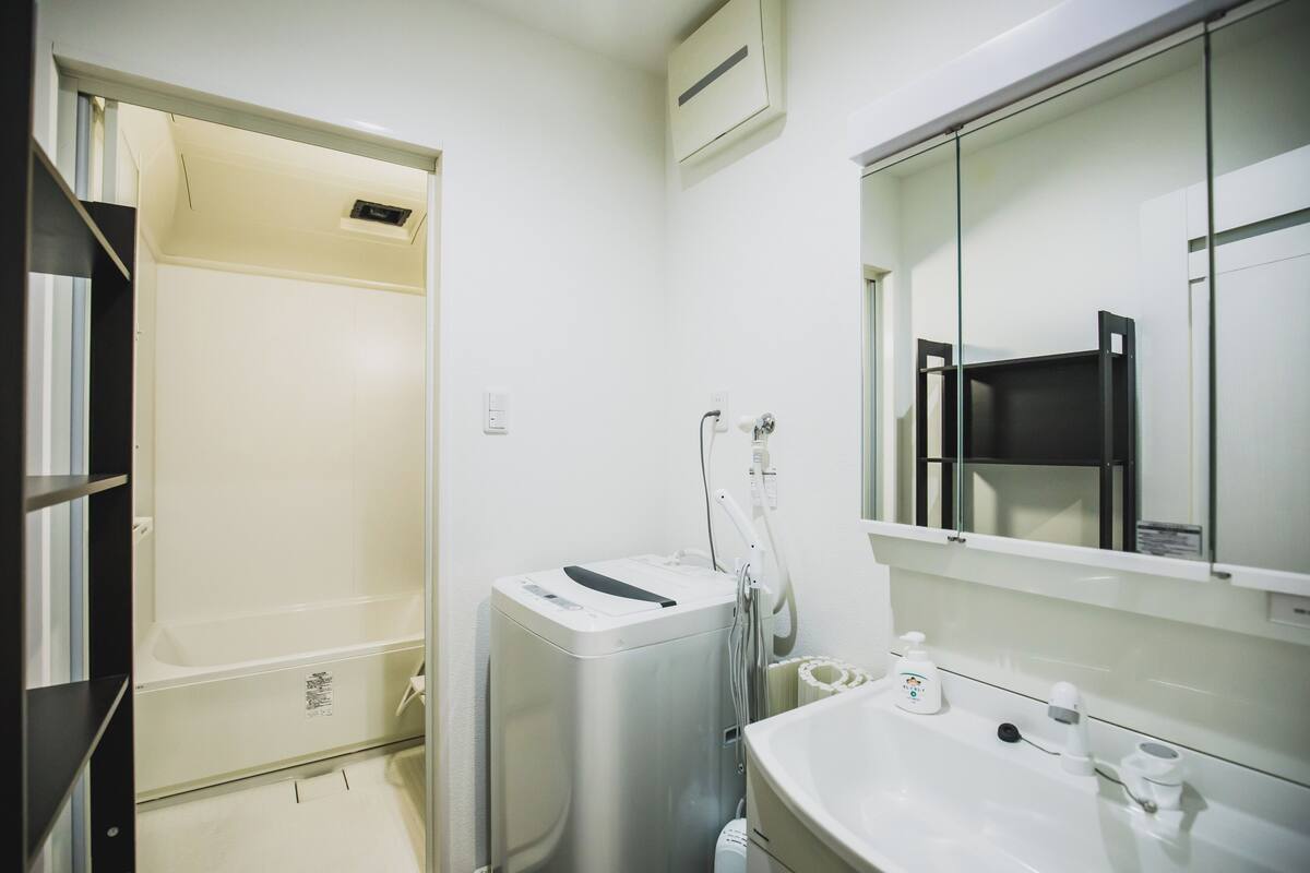 A modern bathroom with a white sink, mirror, and a shower area.