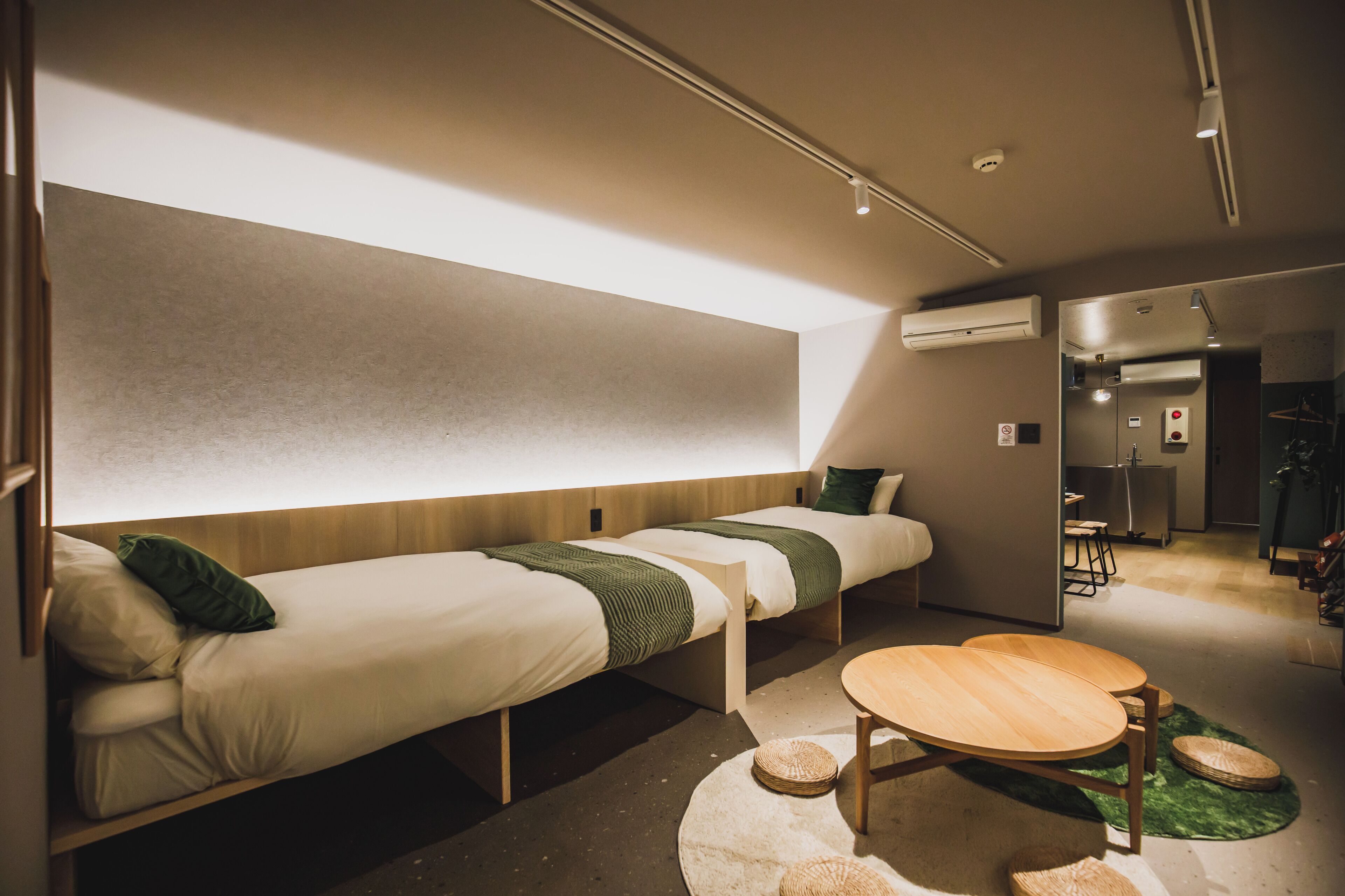 A modern hotel room with two single beds, a wooden table, and a small seating area.