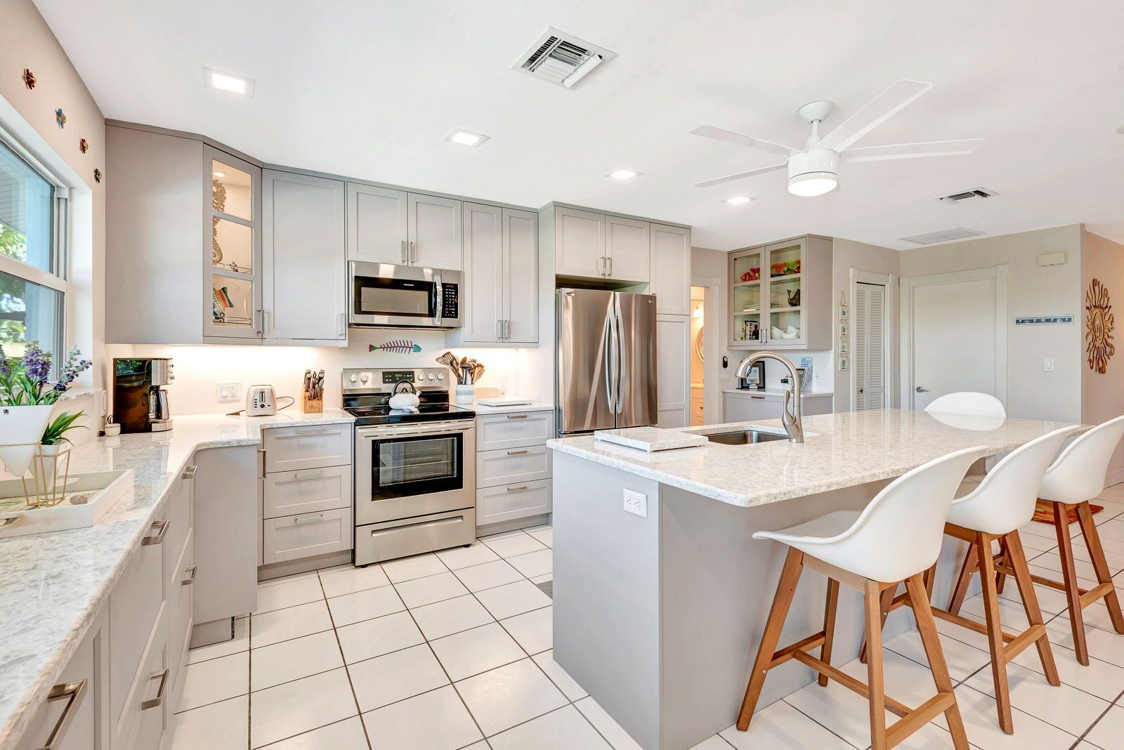 A modern kitchen with stainless steel appliances, a central island with bar stools, and a view of the dining area.