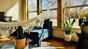 Una habitación con una hamaca, un sofá azul y plantas en macetas.