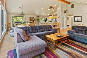 Un salon spacieux avec un grand canapé d’angle, une table basse en bois et un tapis rayé aux couleurs vives.
