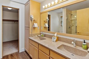 Une salle de bain avec deux lavabos, un meuble-lavabo, un miroir et une douche.