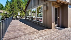 A wooden deck with a covered area, large windows, and a door. - Spacious 6-bedroom house in Sunriver perfect for families/groups (Sunriver)