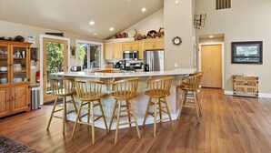 A spacious kitchen with a large island, wooden chairs, and modern appliances. - Spacious 6-bedroom house in Sunriver perfect for families/groups (Sunriver)