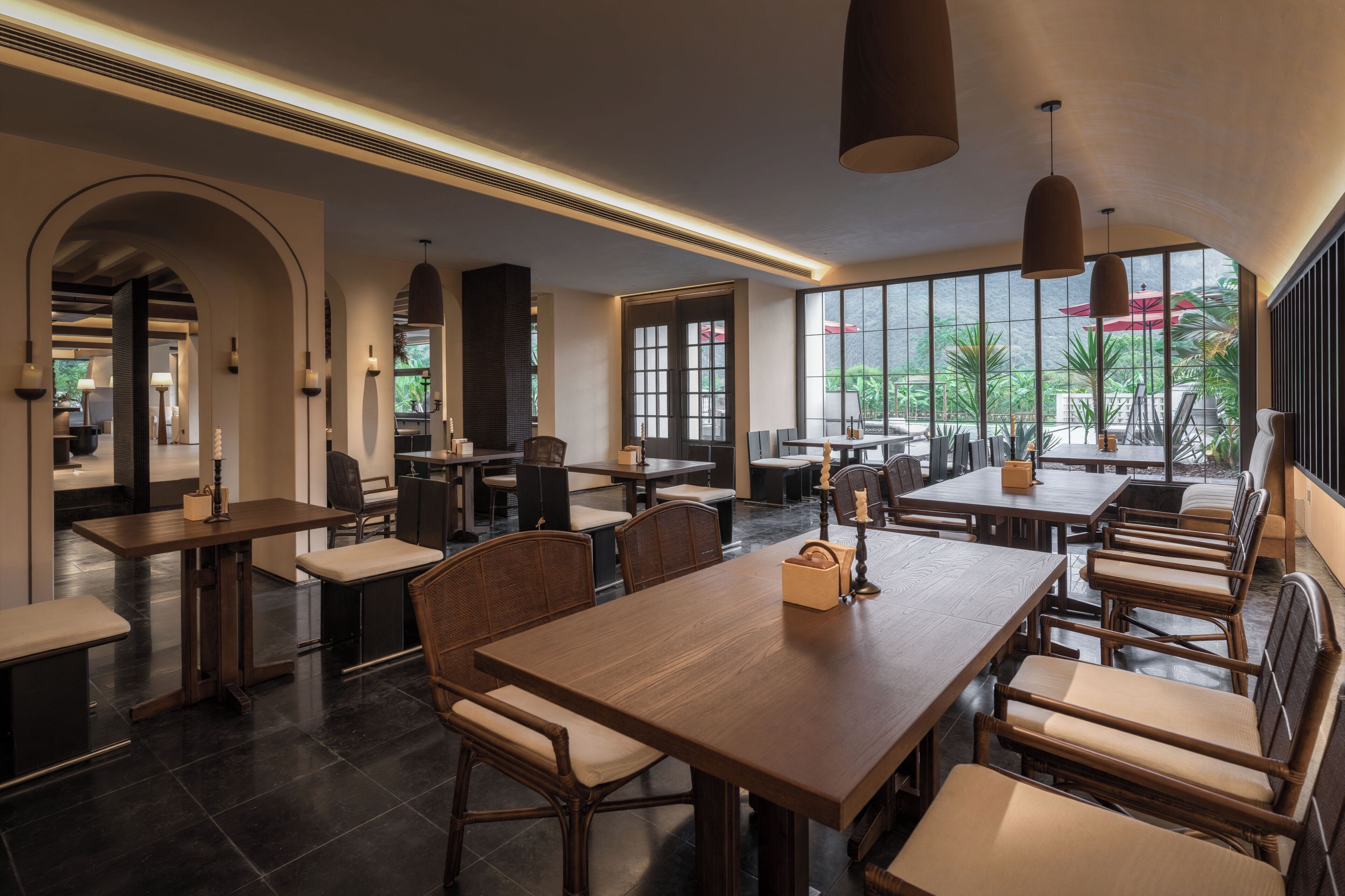 A spacious indoor dining area with high ceilings, large windows, and modern furniture.