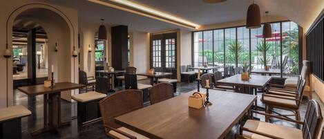 A spacious indoor dining area with high ceilings, large windows, and modern furniture.