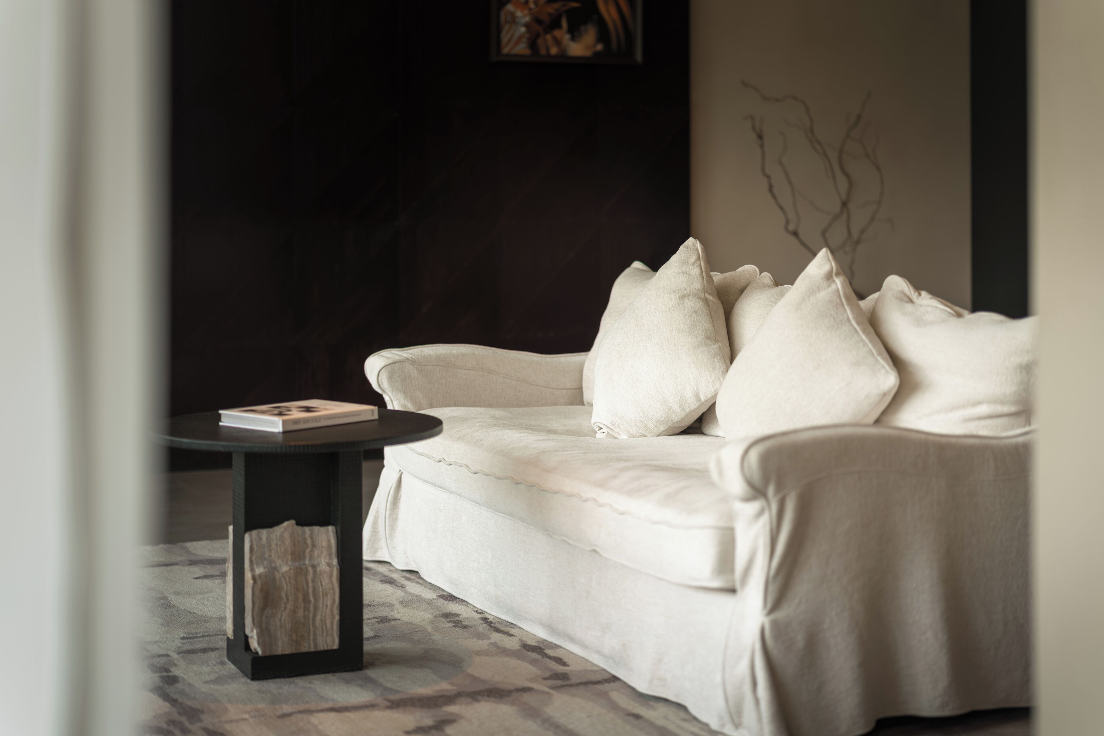A modern living room with a white sofa, a round black coffee table, and a book on the table.