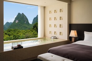 A hotel room with a large window, a bathtub, a bed, and a wall with multiple light fixtures. - The Deer Haven Yangshuo - A Luxury Heritage & Modern Karst Mountain Retreat by Yulong River (Guilin)
