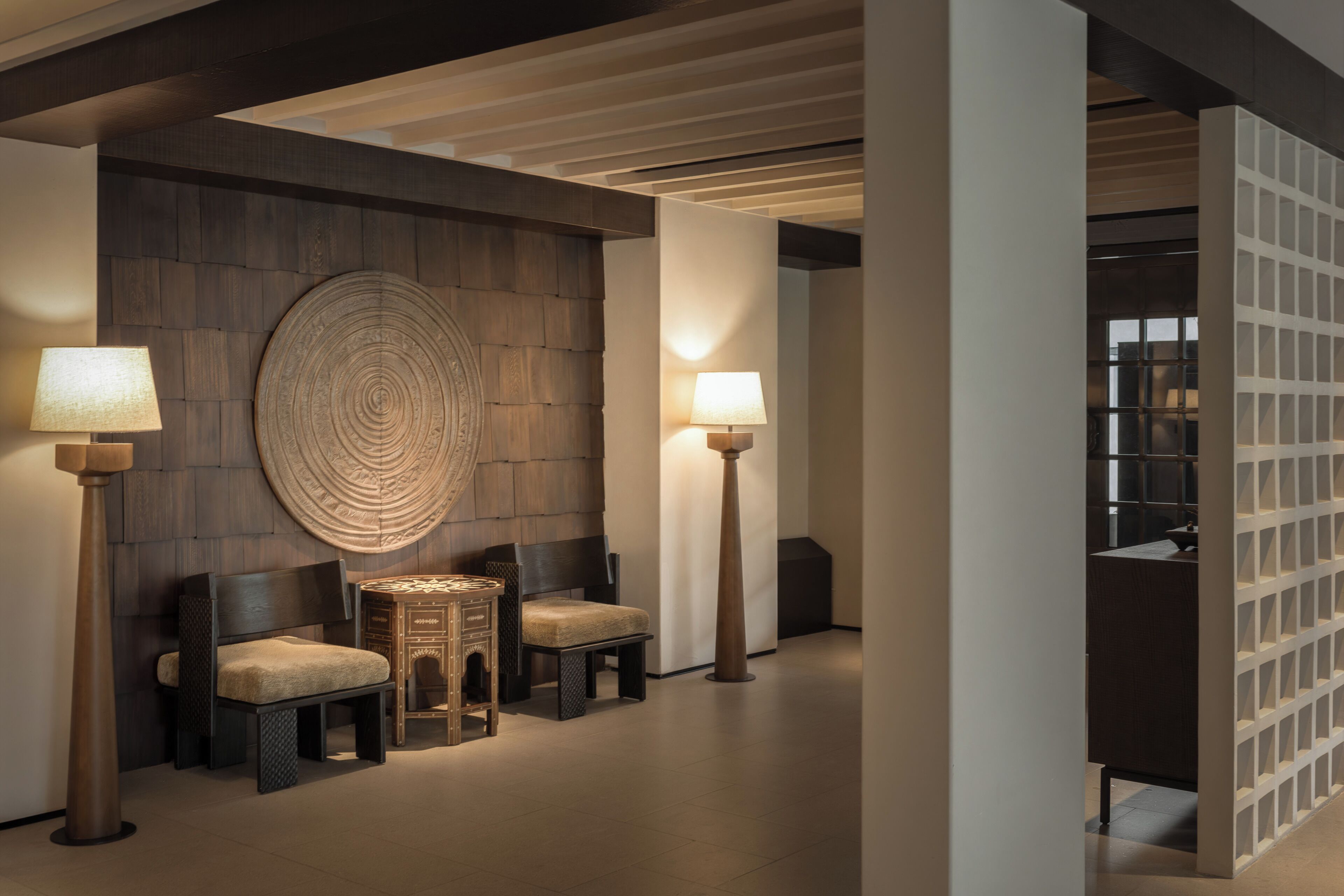 A modern interior with two chairs, a round wall decoration, and two floor lamps.