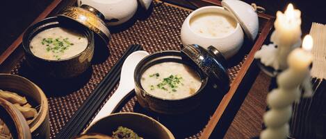 A tray with bowls of soup, a candle, and a traditional Japanese tea set.