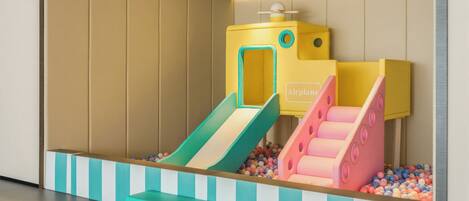 Zona de juegos infantiles con dos toboganes y una piscina de pelotas.