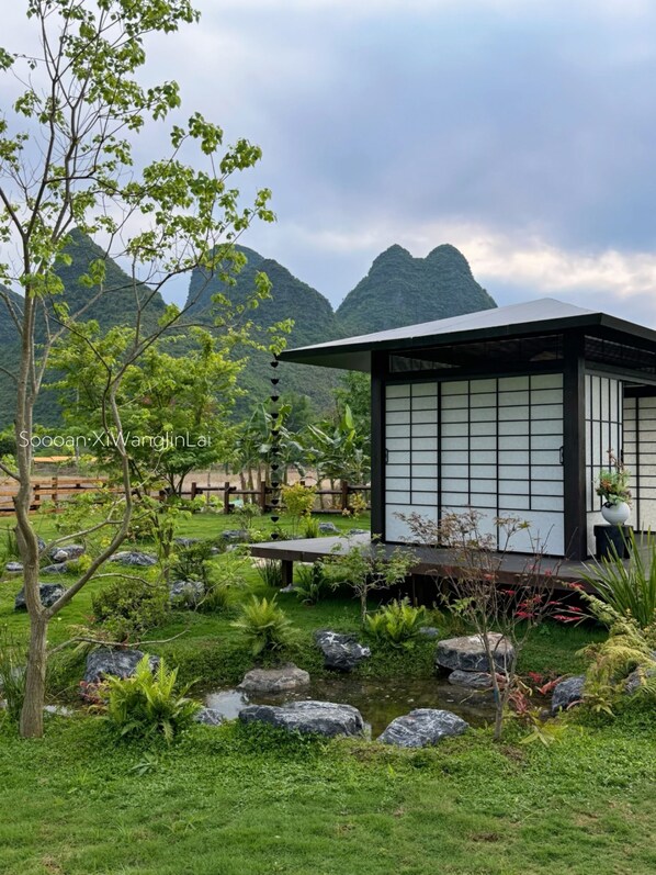 A traditional Japanese-style building with a tiled exterior, surrounded by a well-maintained garden with rocks, ferns, and a small pond. - PastForward Deer Luxury Hidden Retreat at Yulong River  (Guilin)