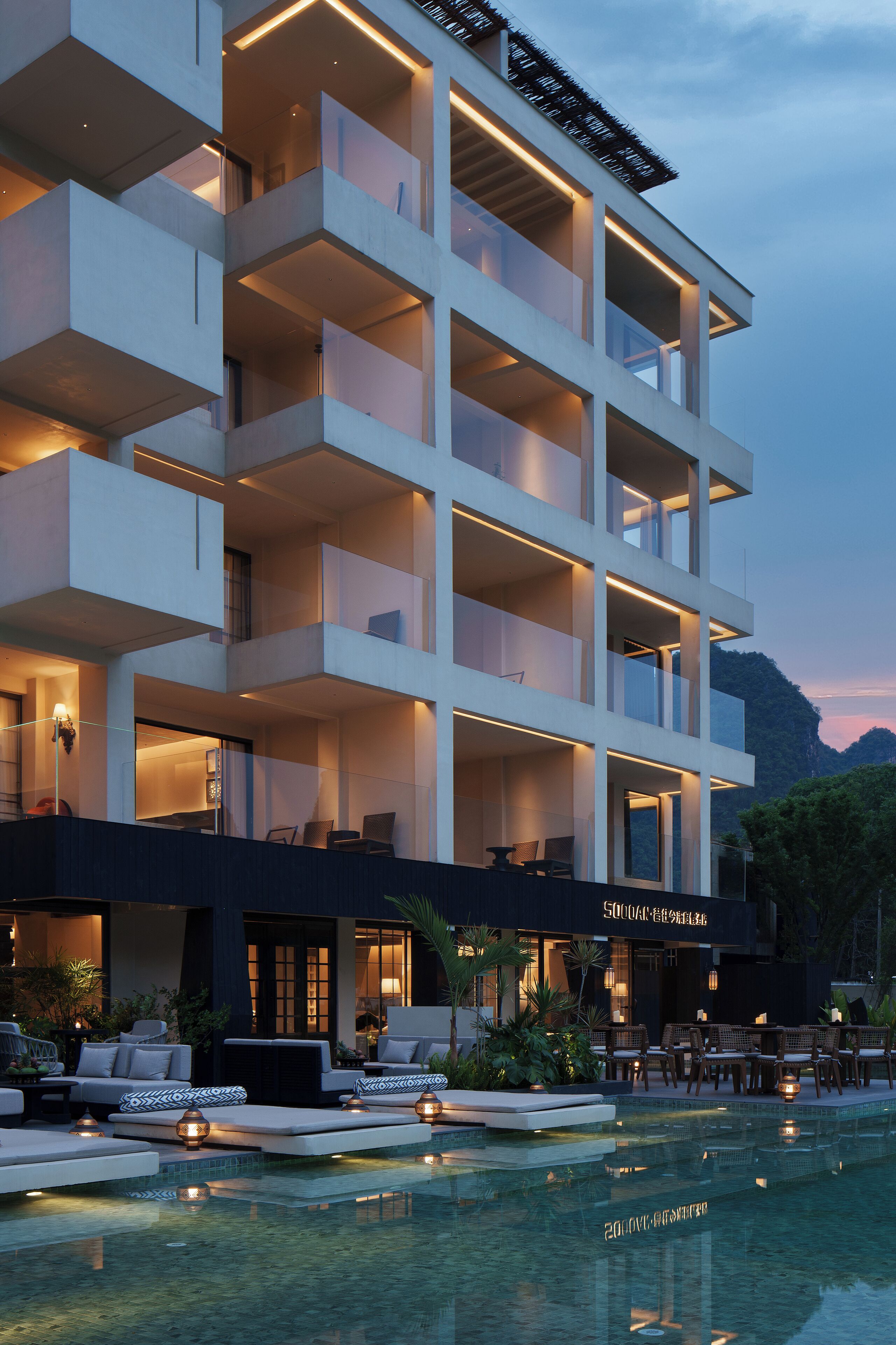 A modern hotel with multiple balconies, a swimming pool, and outdoor seating areas.