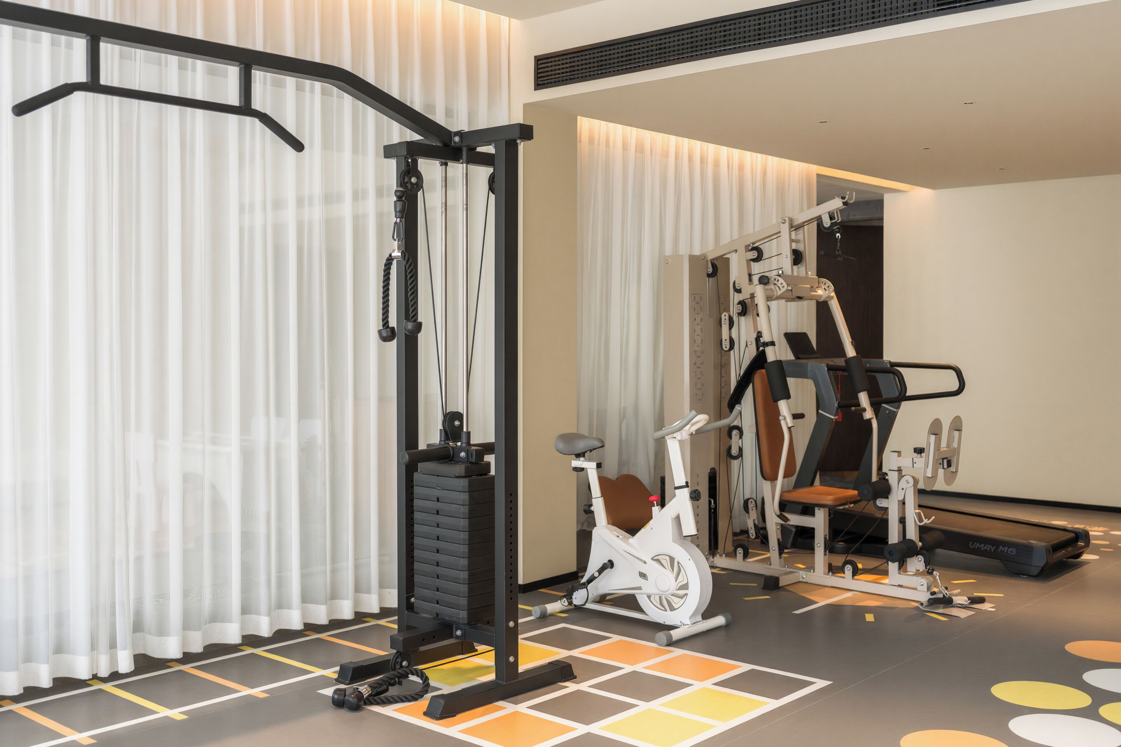 Une salle de sport équipée de matériel d’exercice, d’un vélo d’appartement et d’un téléviseur fixé au mur.