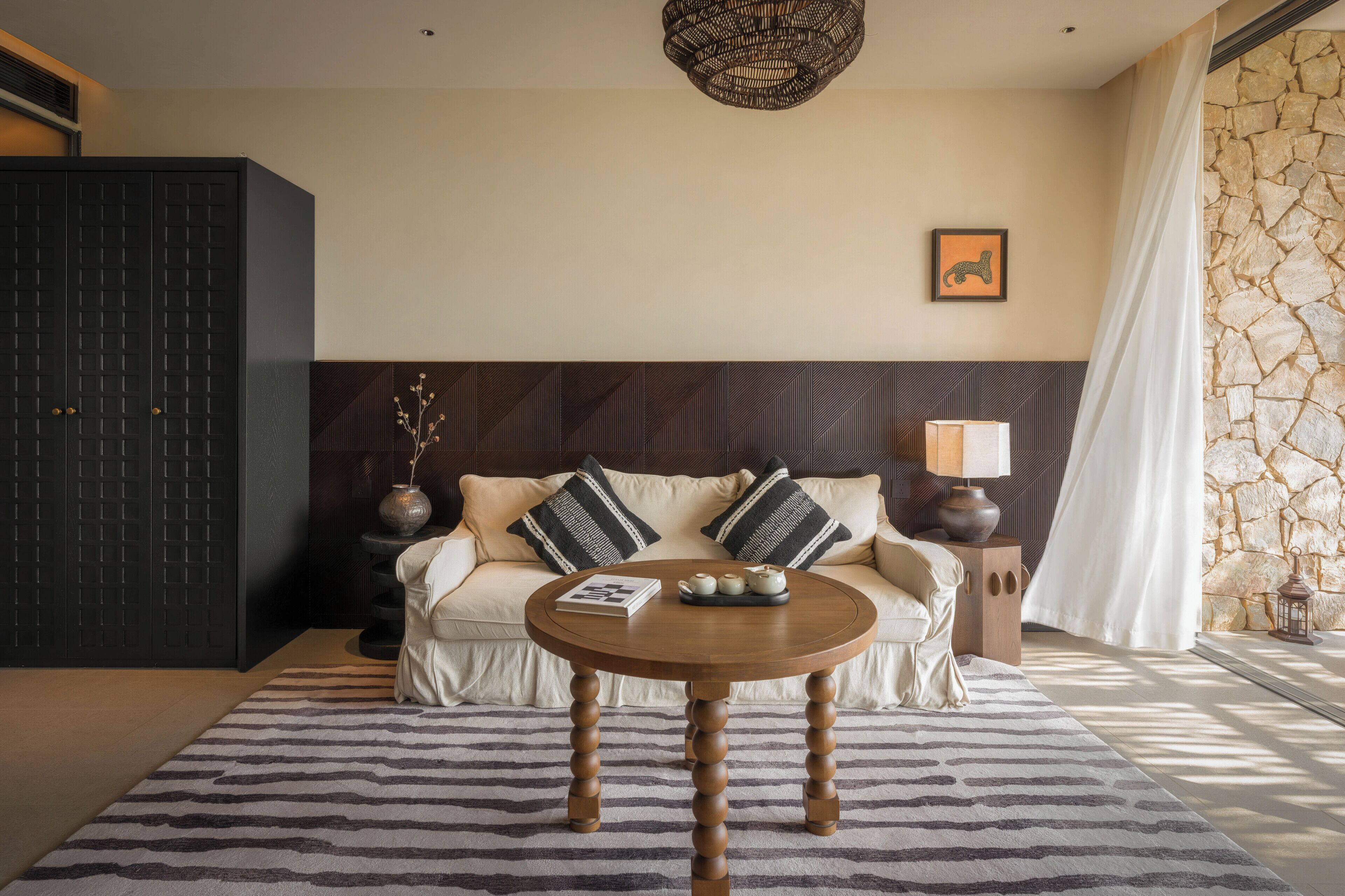Un salon moderne avec un canapé, une table ronde en bois et un mur en pierre.