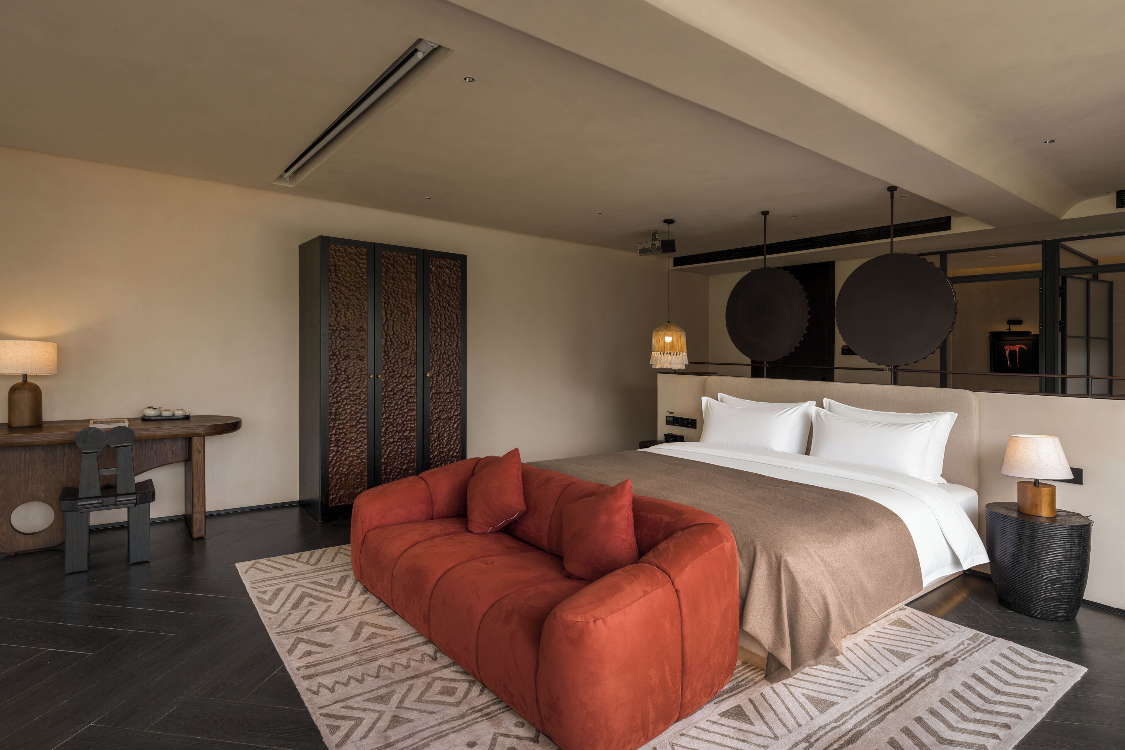 Una habitación de hotel moderna con una cama, un sofá, un escritorio y un espejo grande.
