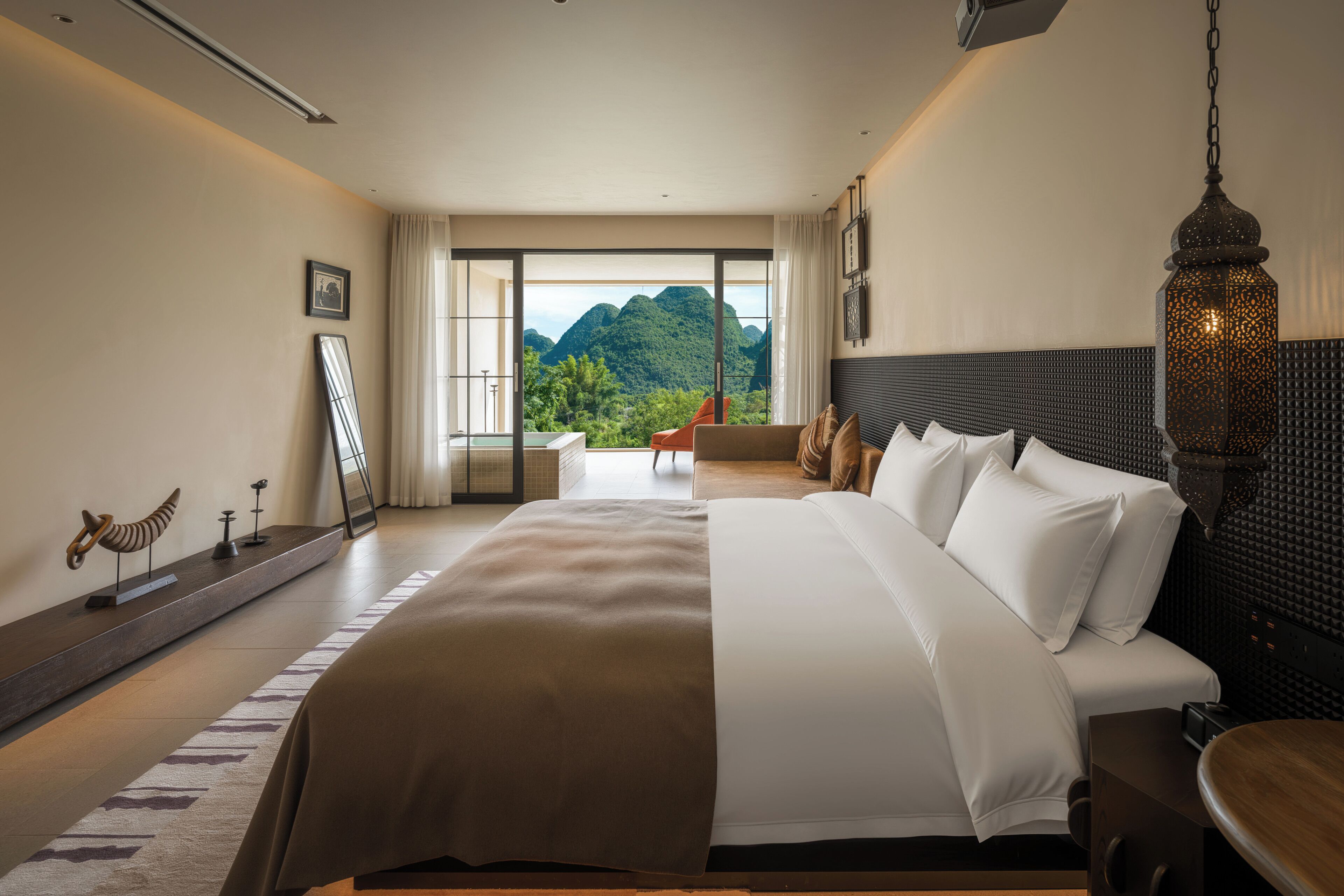 A hotel room with a large bed, a view of mountains, and a balcony.
