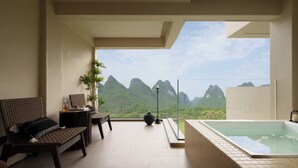 A modern room with a large window, a hot tub, and a seating area with a view of mountains. - The Deer Haven Yangshuo - A Luxury Heritage & Modern Karst Mountain Retreat by Yulong River (Guilin)