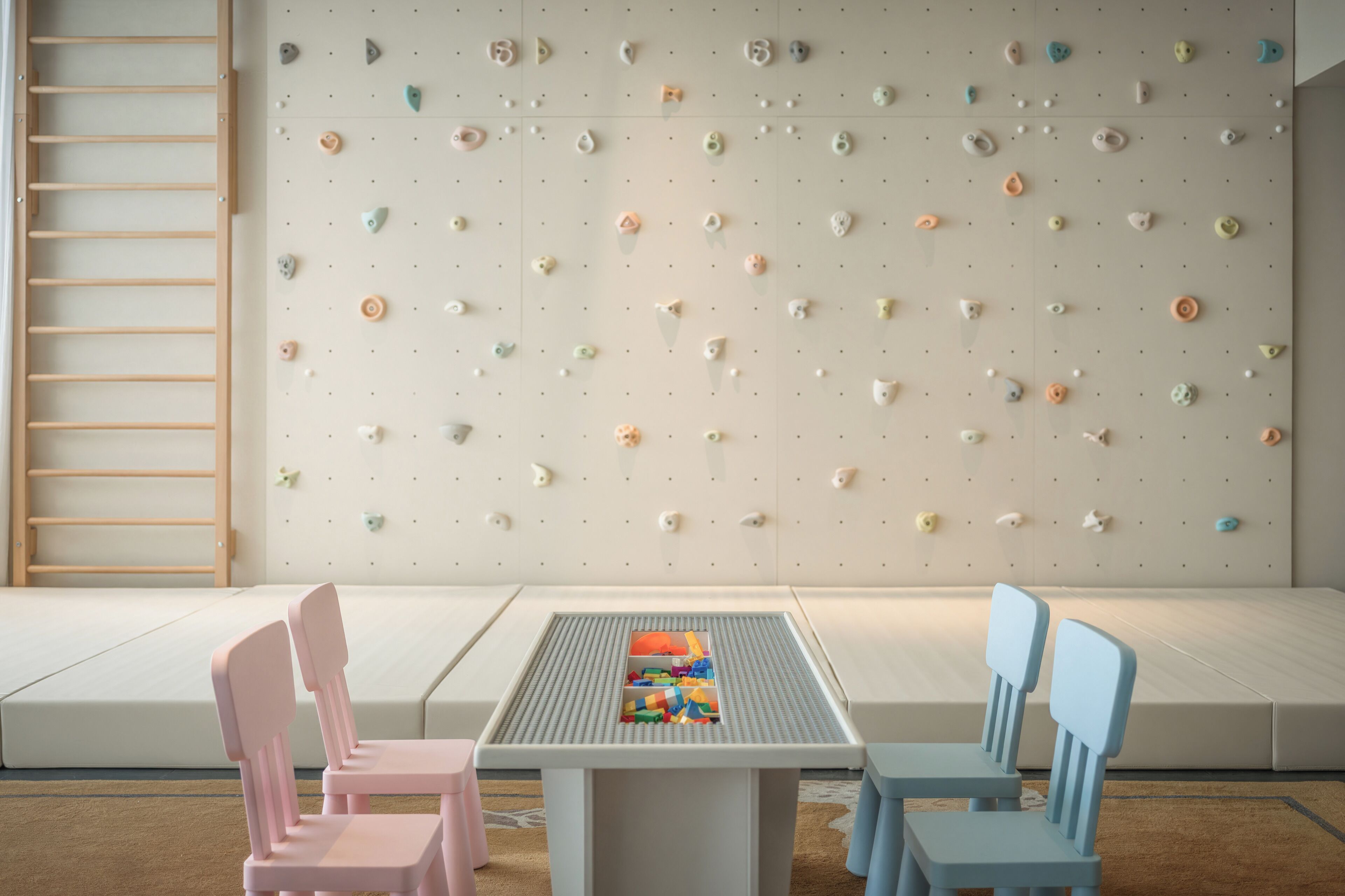 A children's play area with a climbing wall, seating, and a table with toys.