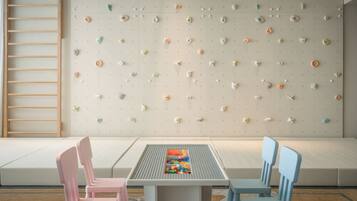 A children's play area with a climbing wall, seating, and a table with toys.