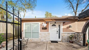 A house with a stone exterior, a white door, and a Texas state emblem on the wall. - PRIVATE 2BR GUESTHOUSE: Food Hub & Easy Freeway Access in International District (Houston)