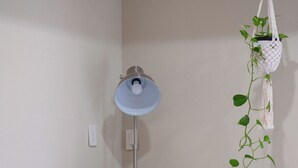 A wicker chair with a white cushion, a globe on a small table, a lamp, and a hanging plant. - PRIVATE 2BR GUESTHOUSE: Food Hub & Easy Freeway Access in International District (Houston)