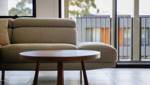 A modern living room with a beige sofa and a round wooden coffee table. - Stylish 2BR Home in Doncaster with parking (Doncaster)