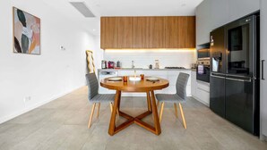 A modern kitchen with a round wooden table, grey chairs, and a black refrigerator. - Stylish 2BR Home in Doncaster with parking (Doncaster)