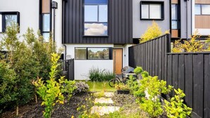 A modern two-story house with a well-maintained garden, a bicycle, and a wooden fence. - Stylish 2BR Home in Doncaster with parking (Doncaster)
